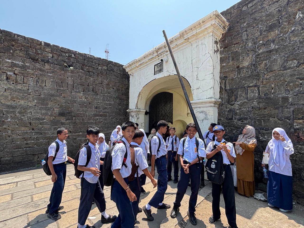 Sekelompok pelajar setempat berseragam sekolah berkumpul di gerbang batu Fort Rotterdam