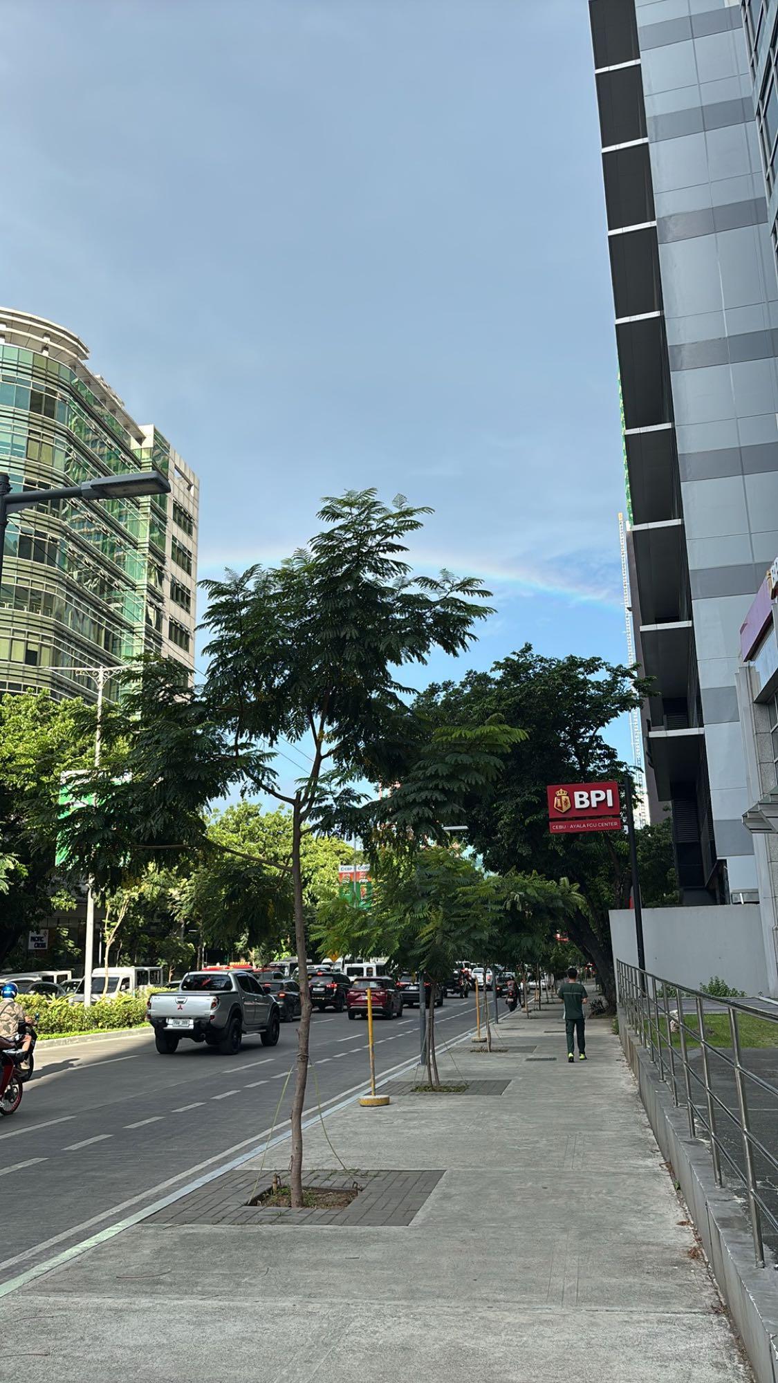 A street near Ayala Center in Cebu with a faint rainbow over the buildings
