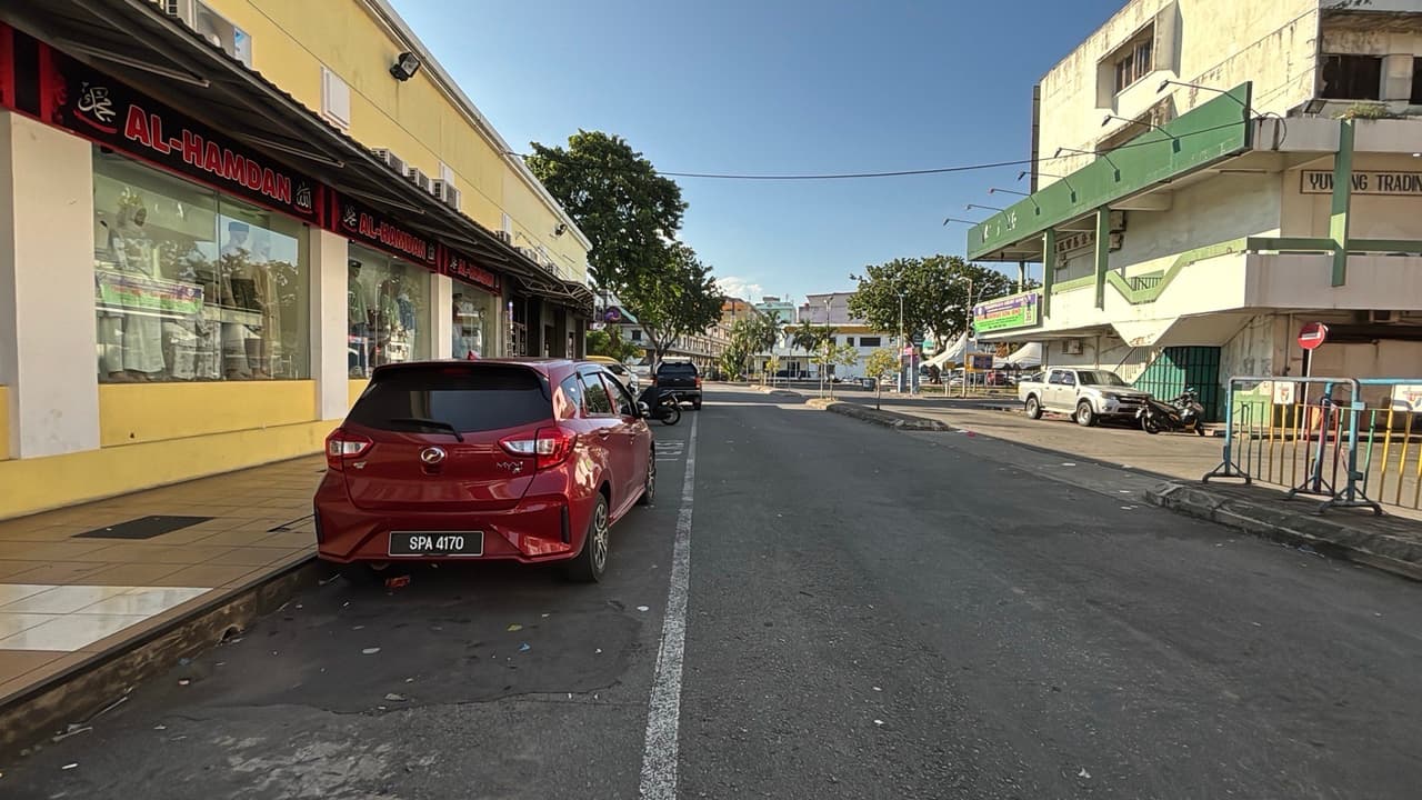 A quiet daytime street in Tawau lined with shophouses