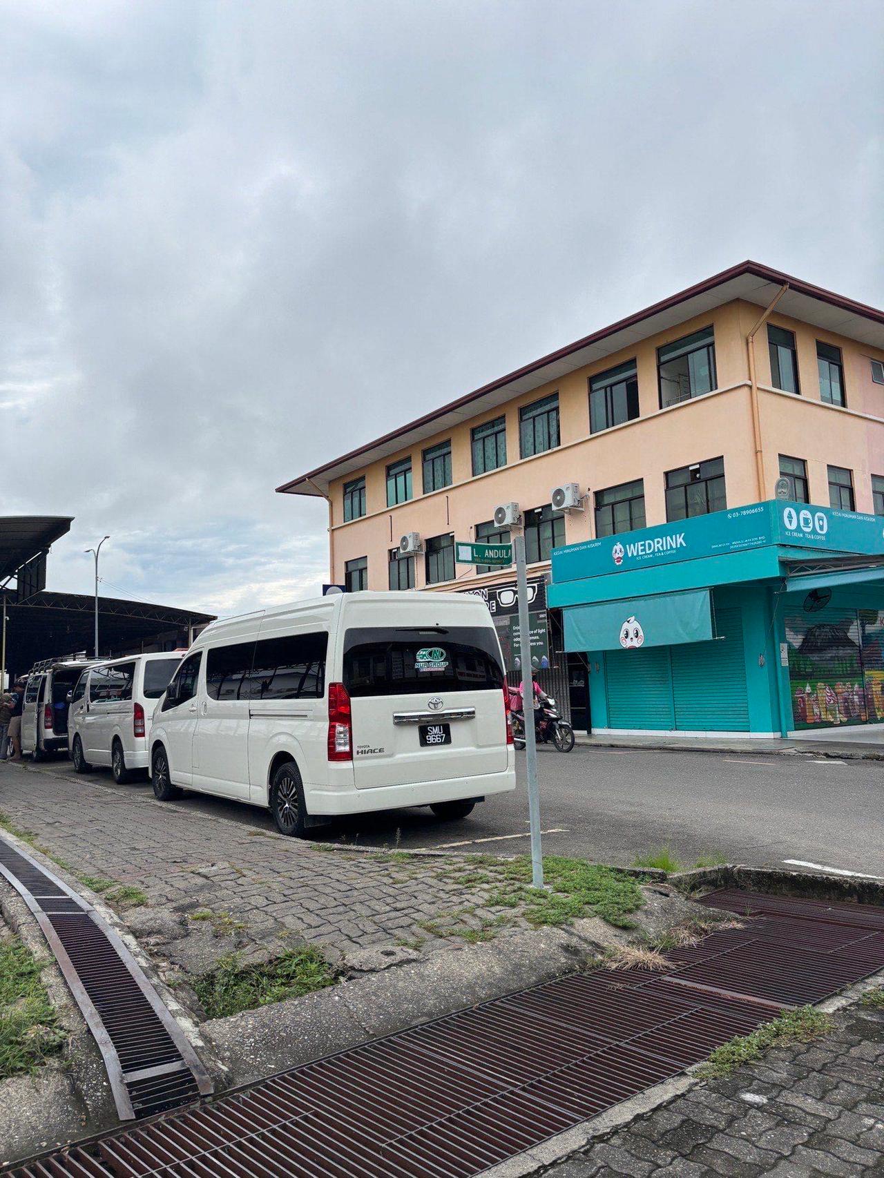 A row of white vans parked at the Keningau bus terminal