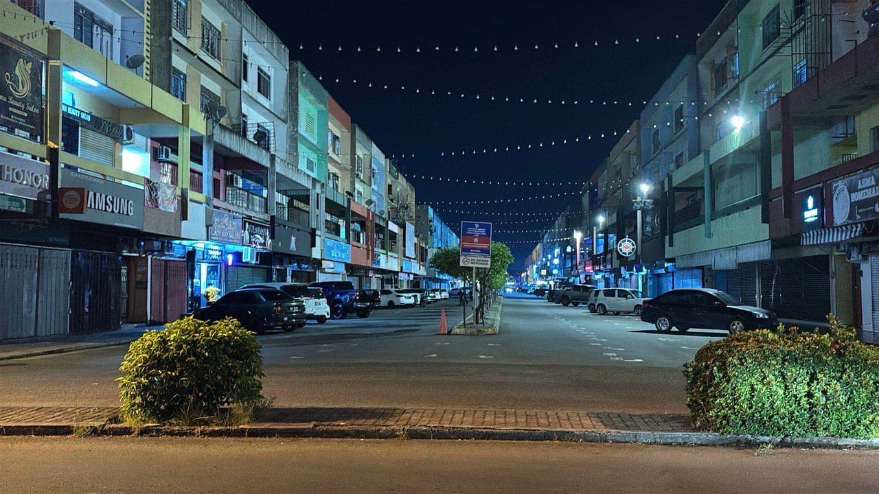 A quiet, colorfully lit street in downtown Tawau at night