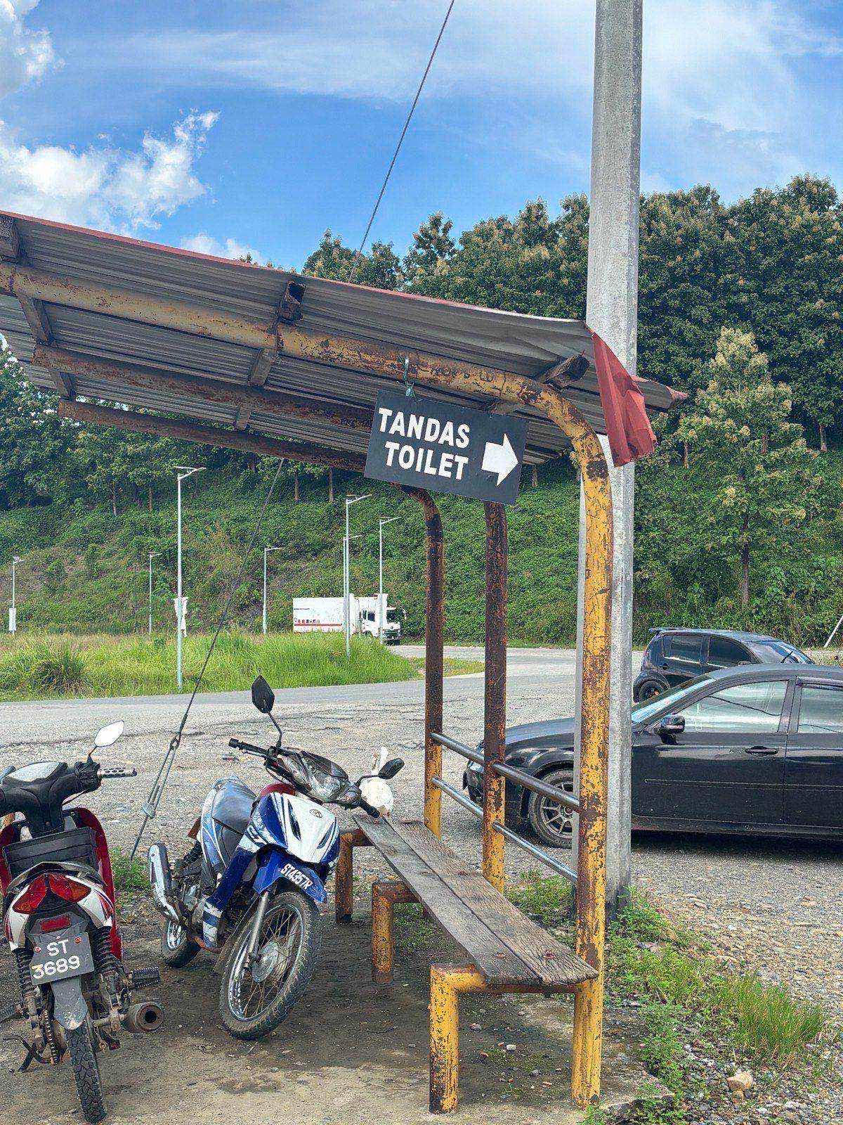 A roadside rest stop with a "Toilet" sign and parked motorbikes