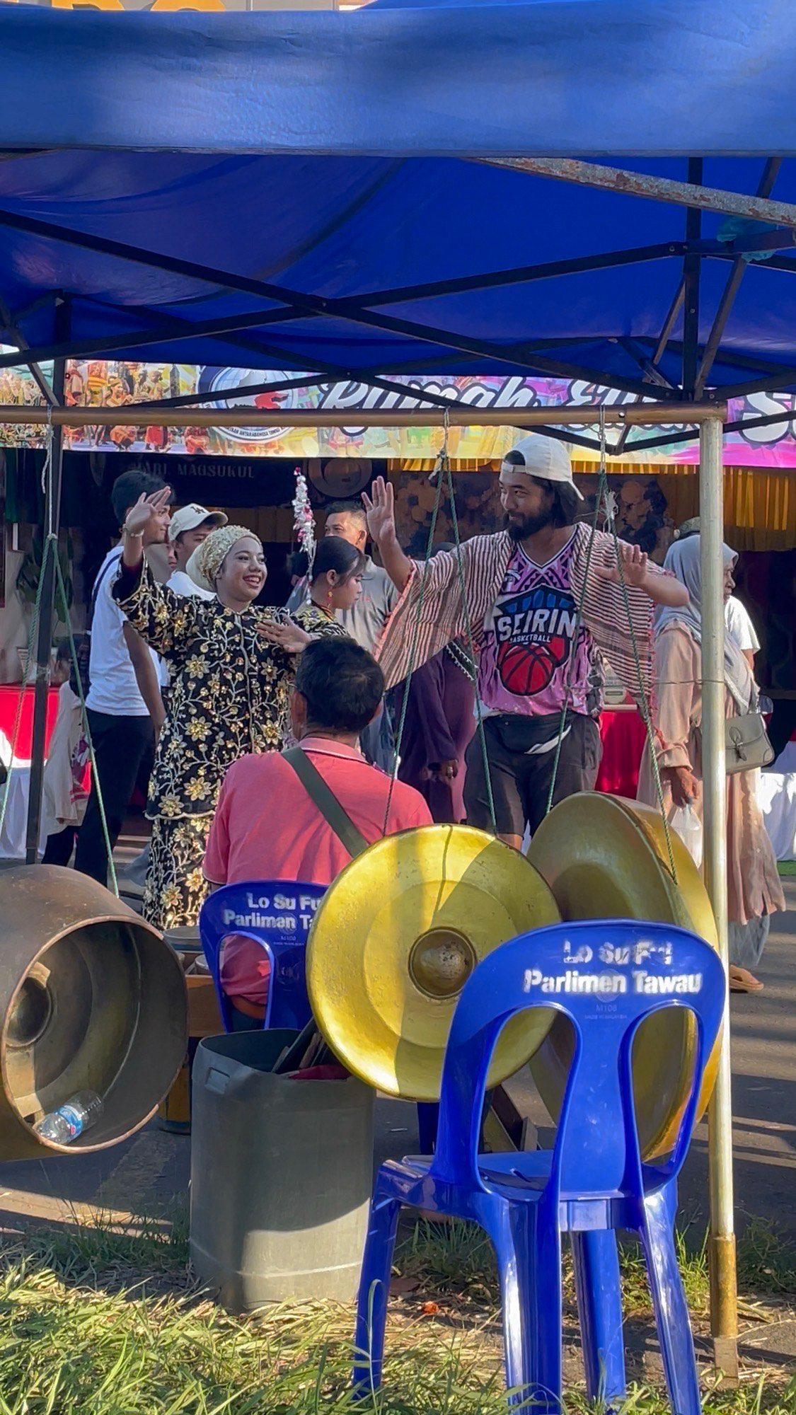 Dancing with hands raised alongside performers at the Siluk booth