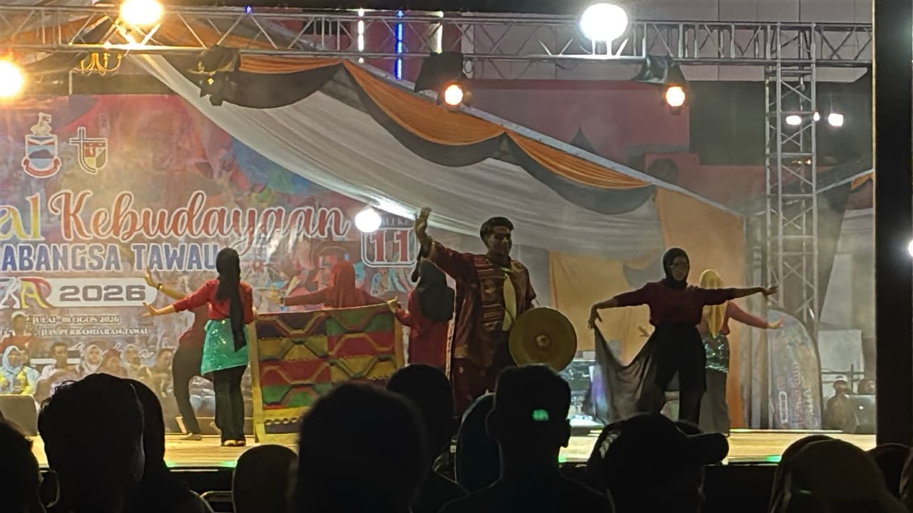 Traditional dancers performing with a gong on the main stage at night