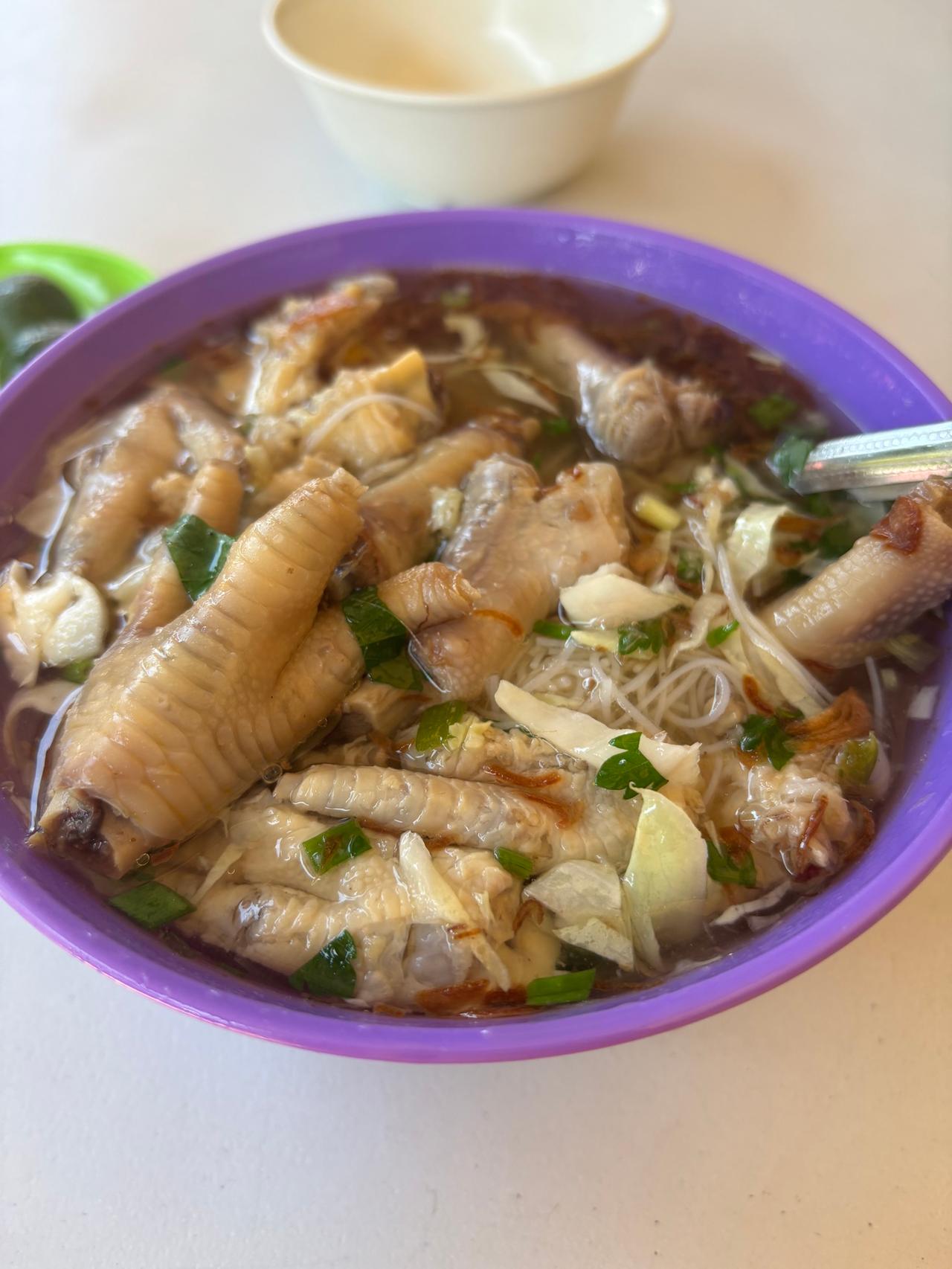 A purple bowl of Sup Kaki Bihun, rice vermicelli soup loaded with chicken feet
