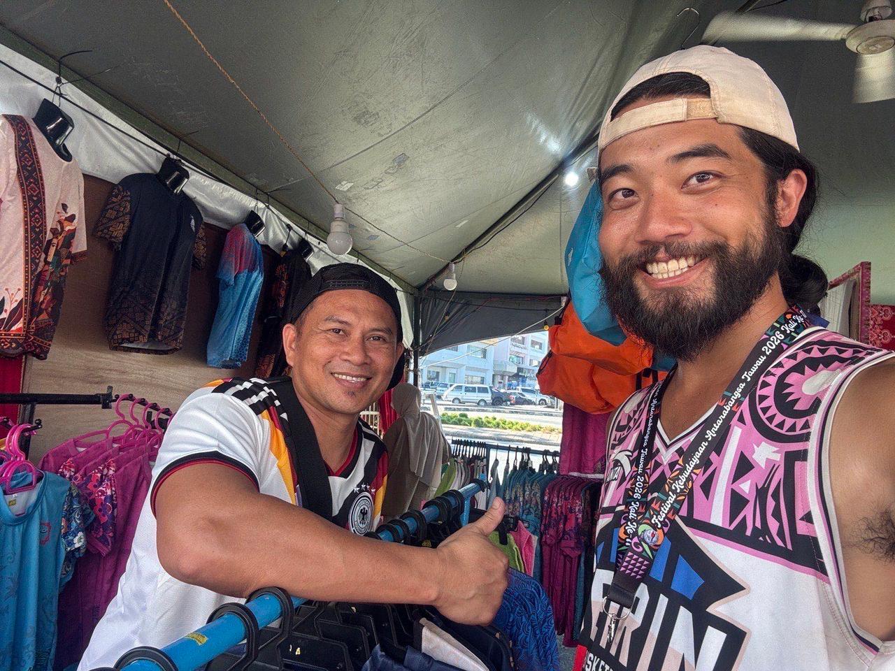 Posing with the vendor after buying a festival lanyard at his clothing stall