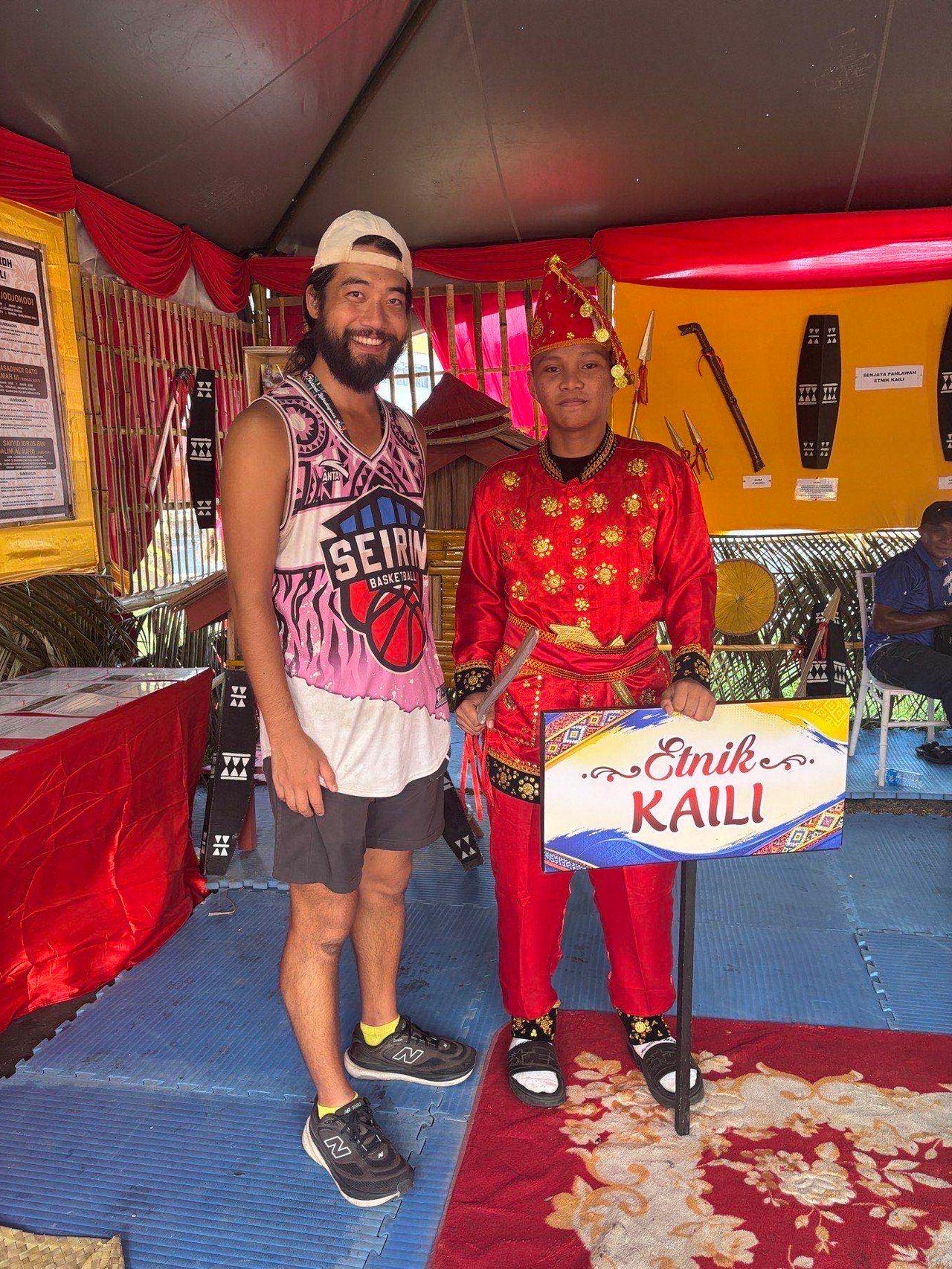 Posing with a costumed guide at the "Etnik Kaili" booth signboard