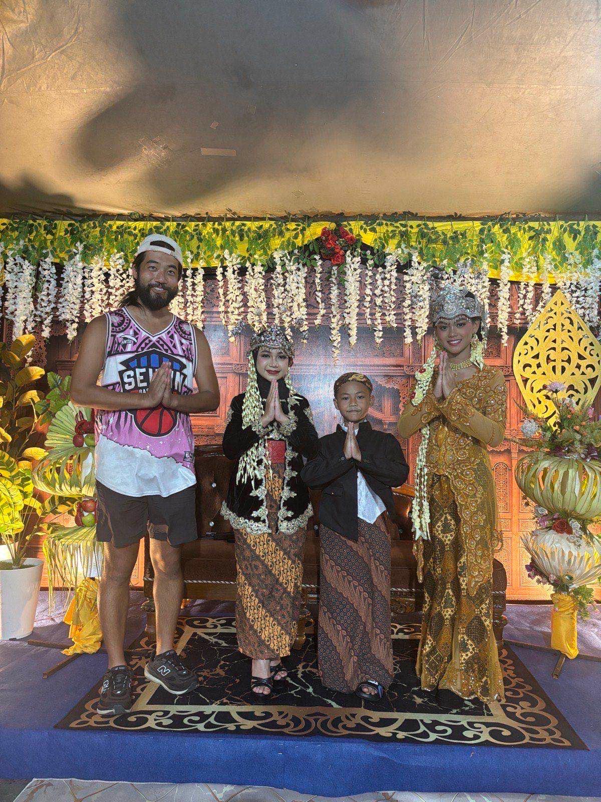 Posing with performers in ornate gold Javanese traditional costumes