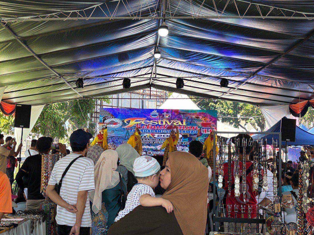 A crowd gathered under a festival tent watching a traditional performance on stage