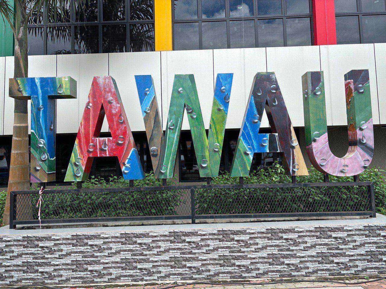 A large colorful "Tawau" sign in front of a modern building