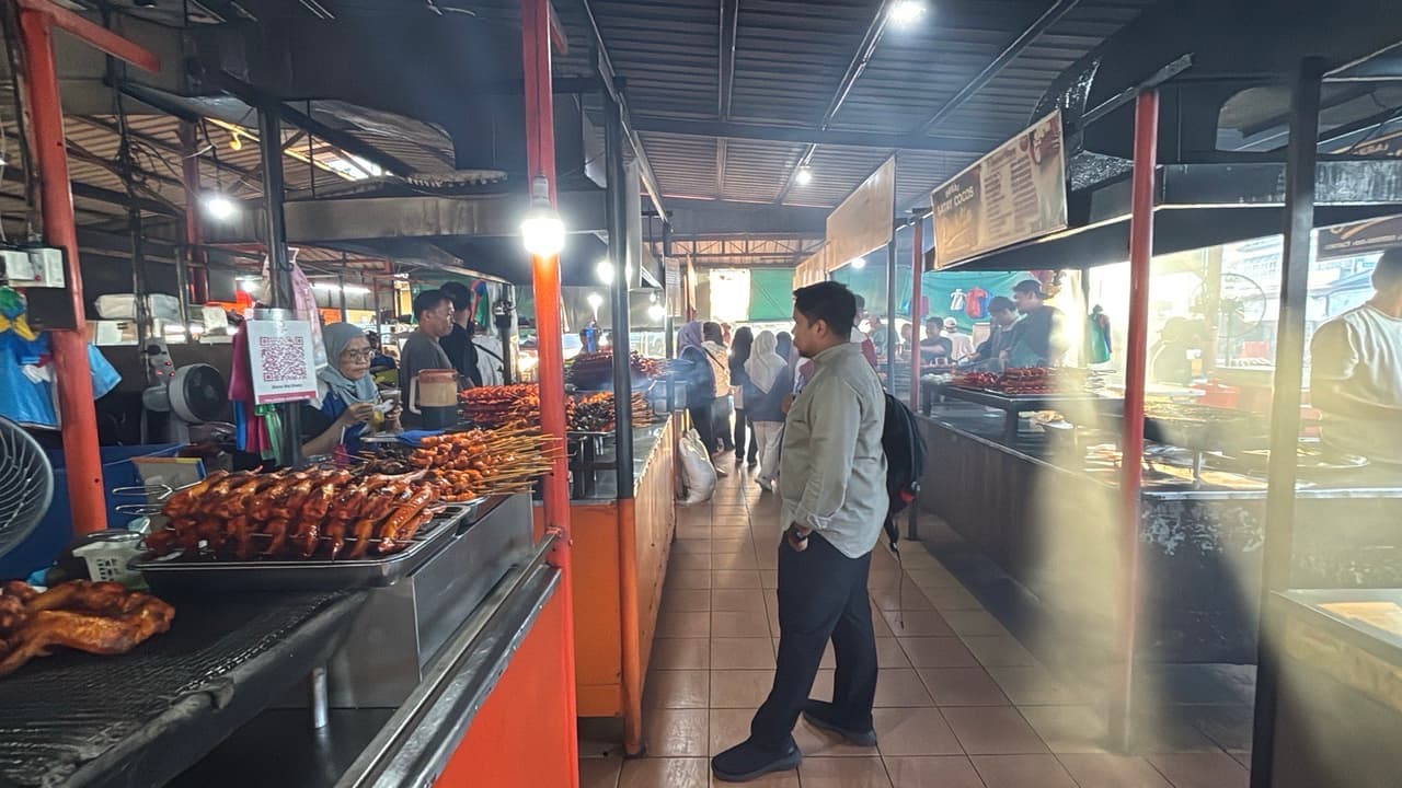 Walking past a row of satay stalls inside a covered market