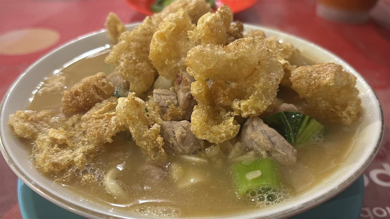Semangkuk sup dengan daging babi dan kerupuk kulit babi goreng untuk makan malam