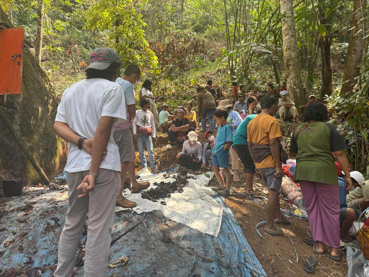 A large crowd of villagers and children gathered around a tomb during the cleaning ritual