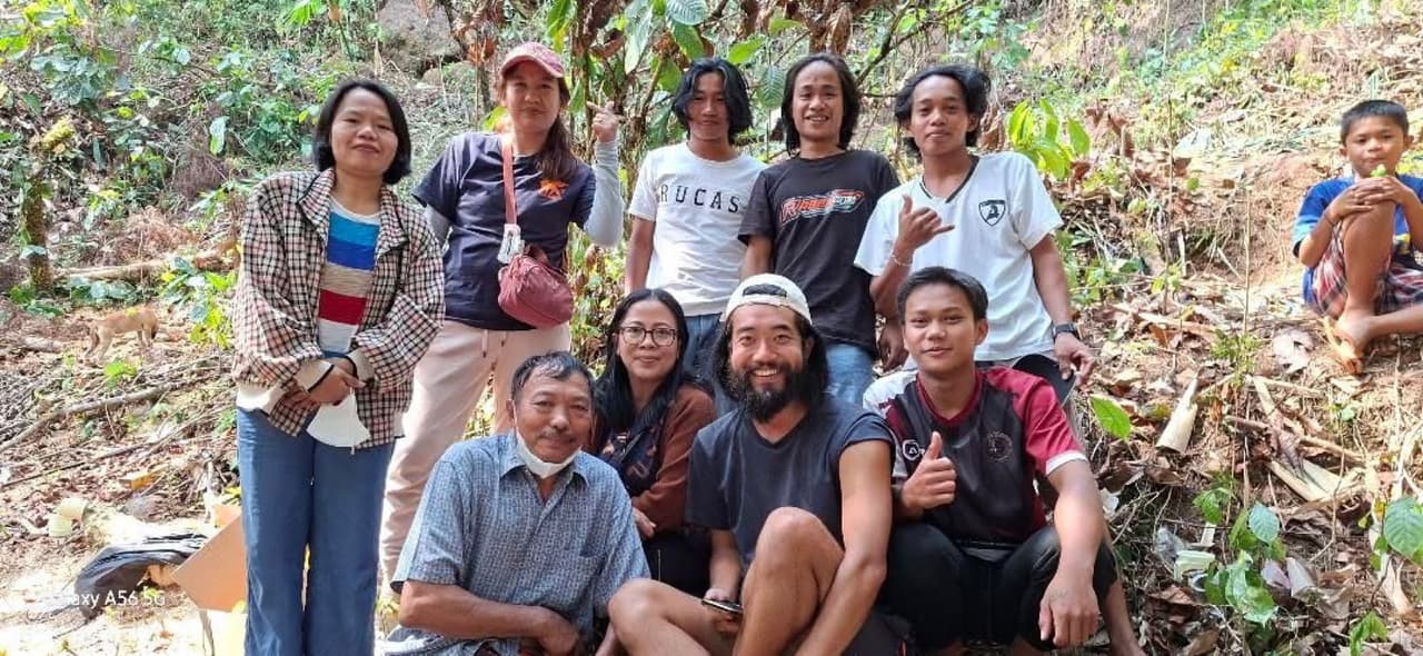 A group photo with local villagers and friends smiling together in the forest after sharing Ballo