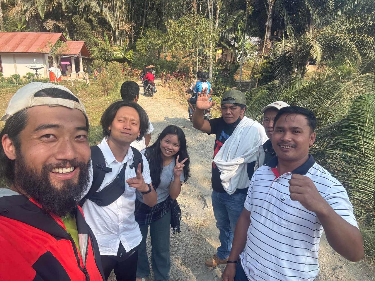 A group selfie with the author, friends and local villagers smiling together on a dirt road