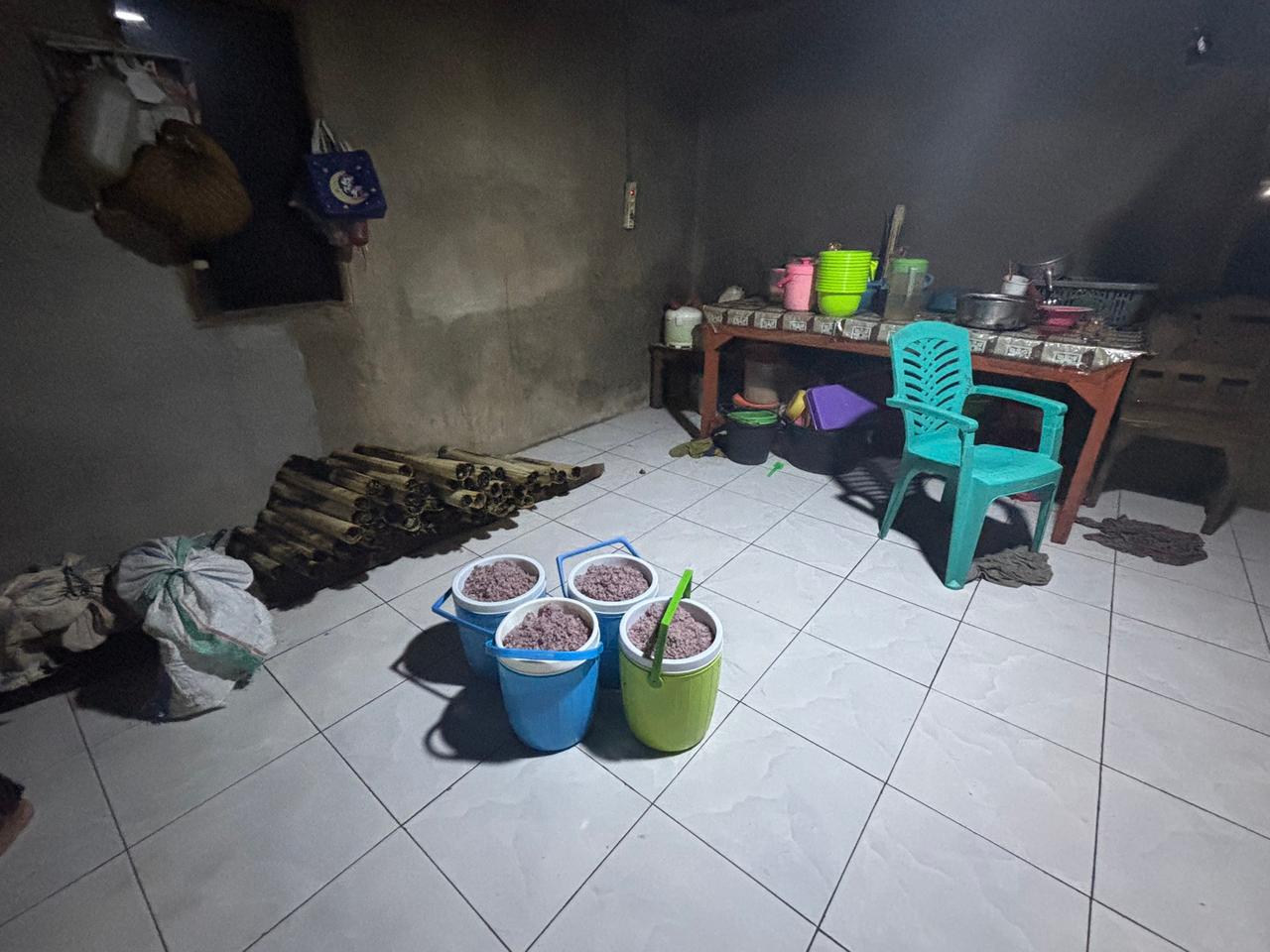 Four large buckets filled to the brim with cooked rice on a tiled floor