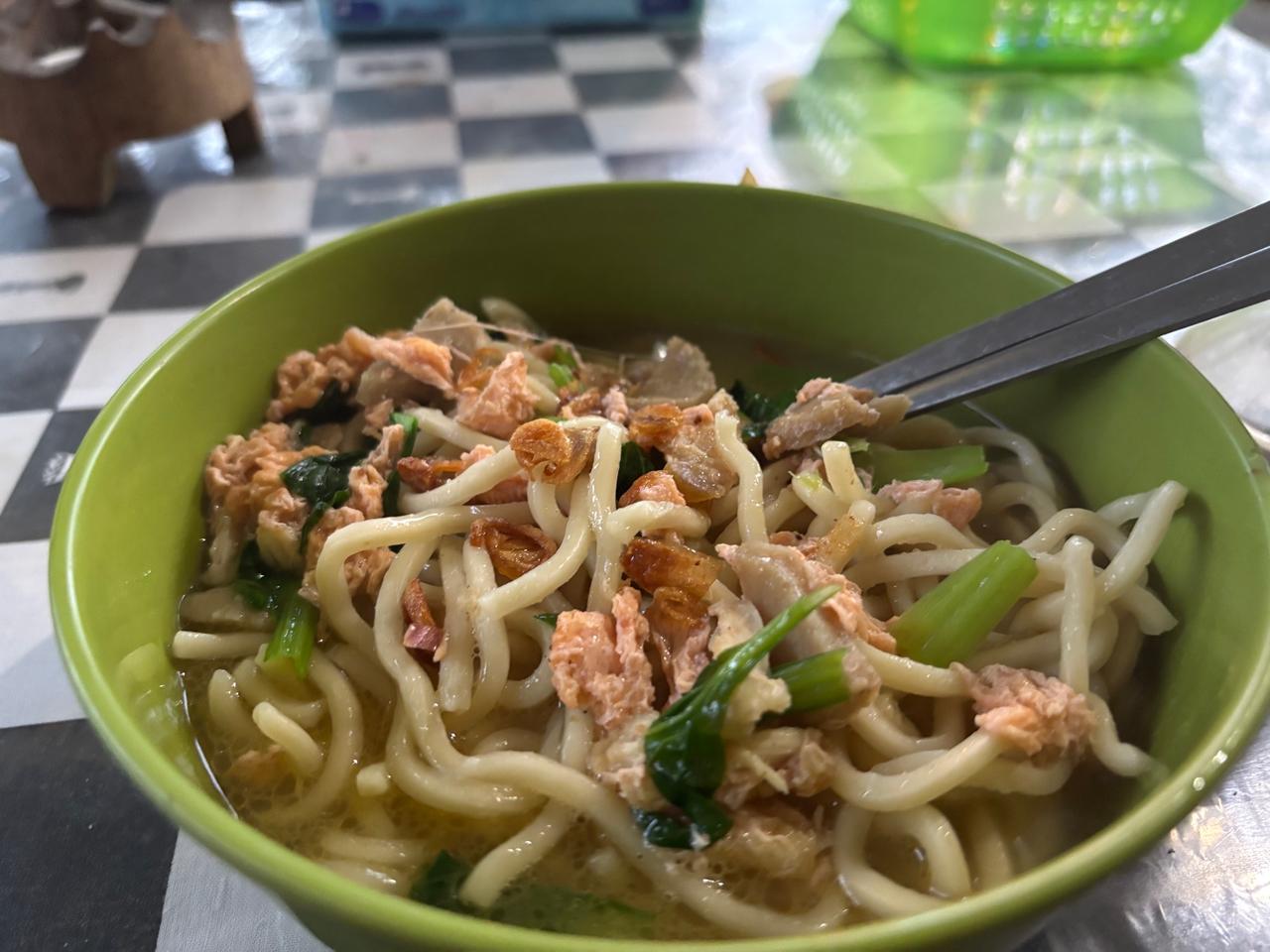A bowl of Mie Kuah noodle soup topped with shredded chicken and fried shallots