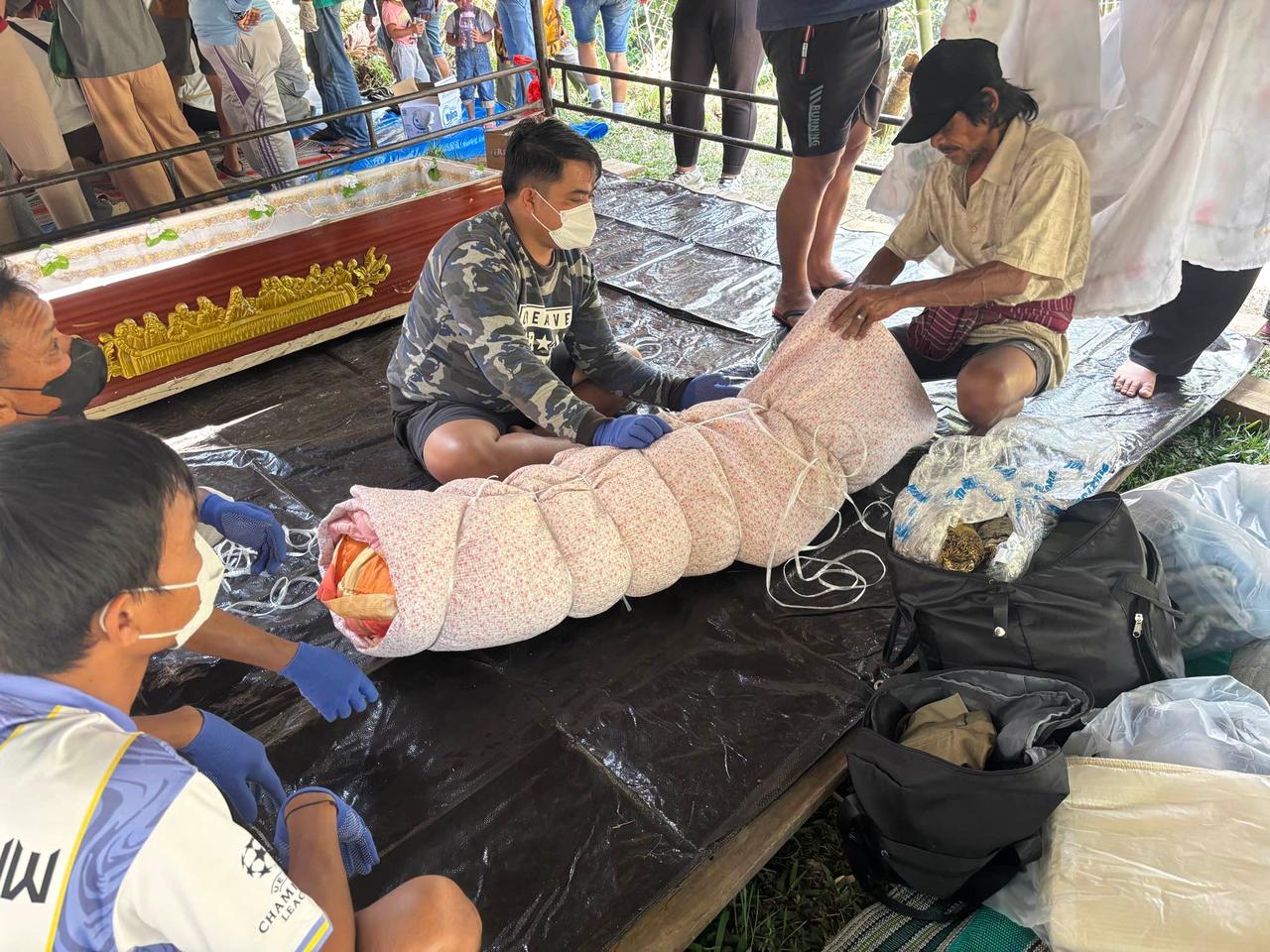 Family members gently rewrapping a mummified ancestor in fresh patterned cloth
