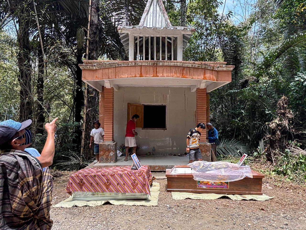 Two prepared coffins draped in traditional cloth resting outside a family mausoleum