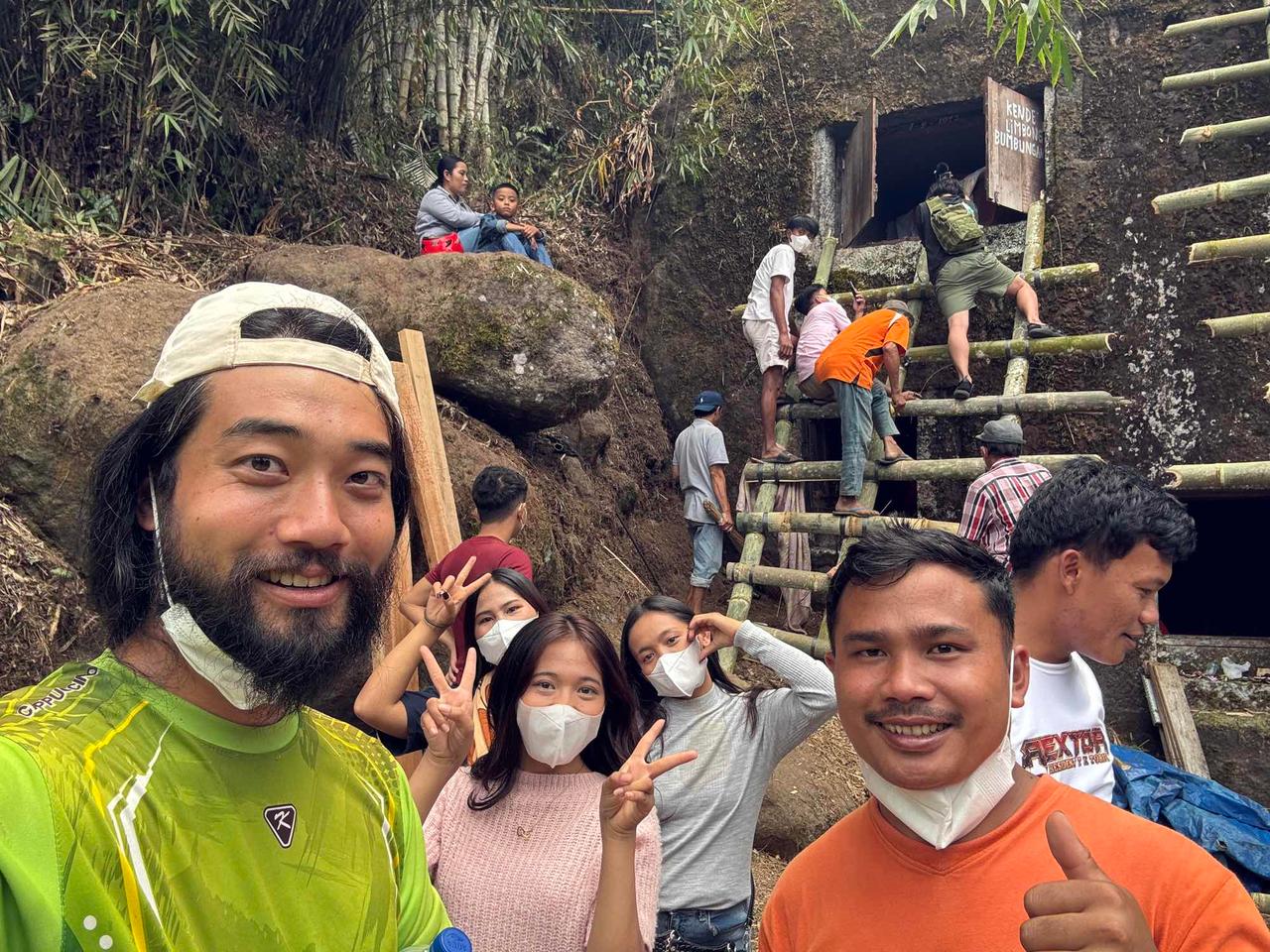 A group of foreign travelers wearing face masks posing together near the rock tomb