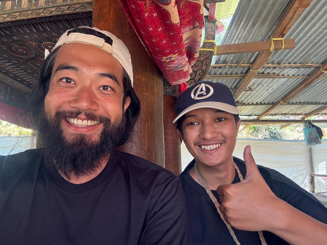 A selfie with a young local named Alvaro giving a thumbs up under a traditional roof