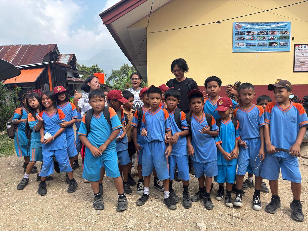 A group photo with an elementary school teacher and his students in uniform outside their school