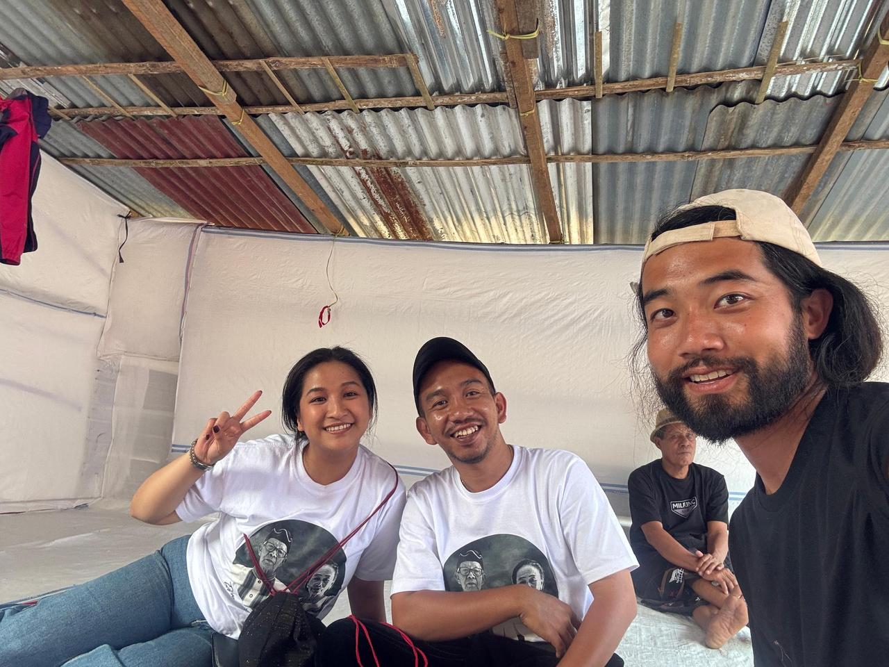A photograph with two family members wearing matching memorial t-shirts printed with a portrait of the deceased