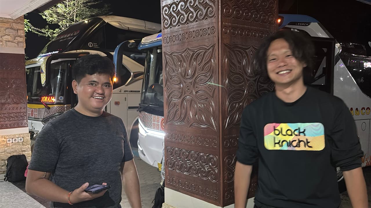A nighttime photo with a friend in front of parked overnight buses bound for Toraja