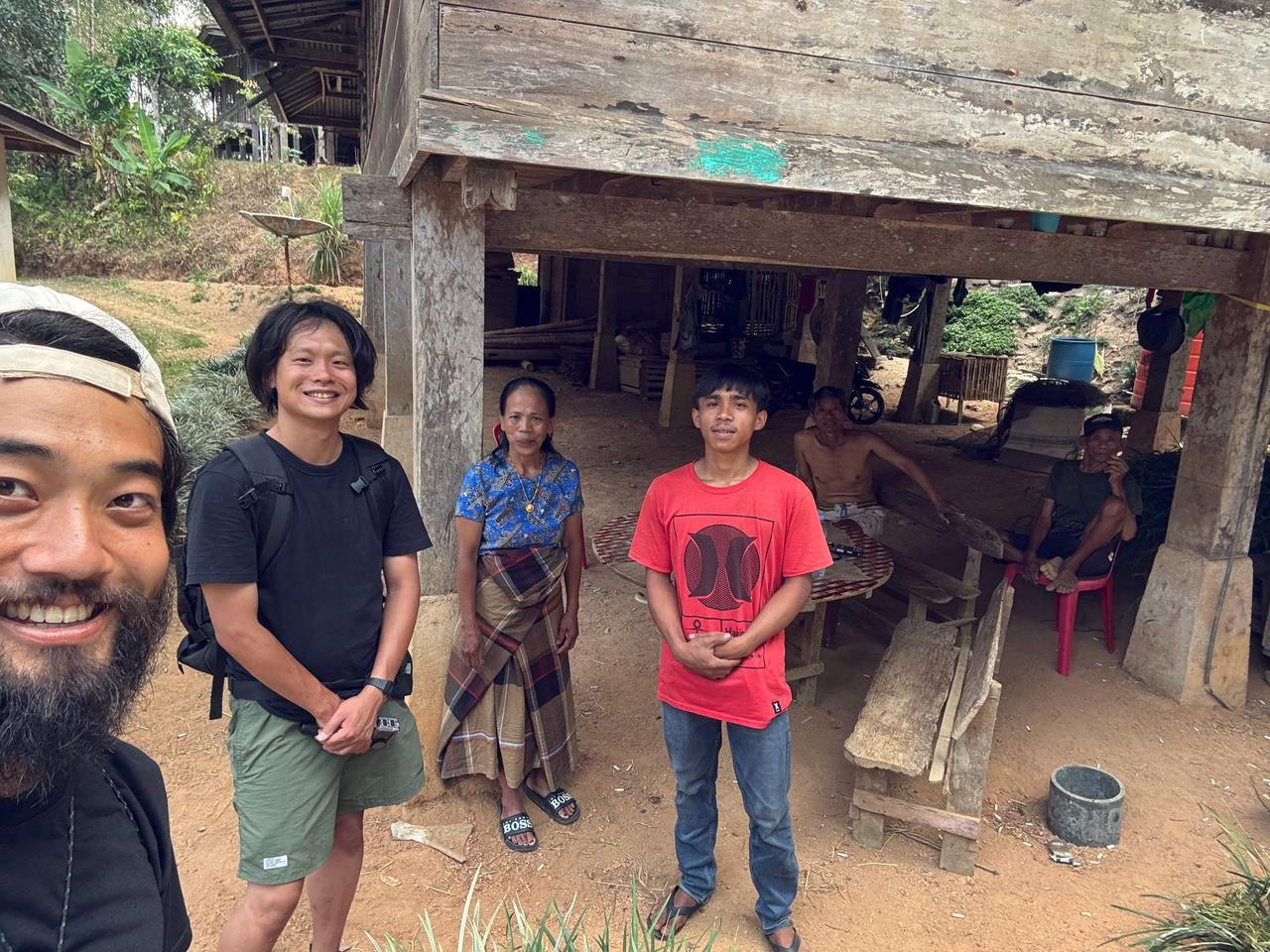 A group photo with the buffalo breeder and his family gathered beneath a traditional rice barn