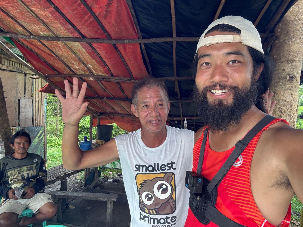 Sharing a peace sign with a local host under a red tarp shelter