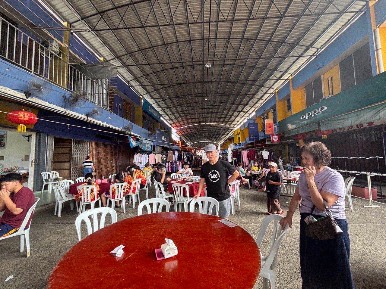 An outdoor restaurant street lined with round tables in Tenom