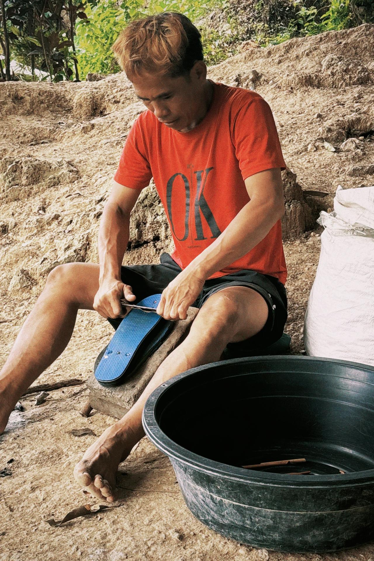An elderly local man carefully rolling raw tobacco by hand