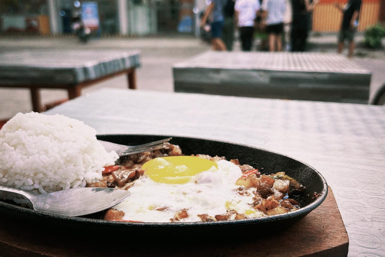 Sizzling sisig with fried egg on a hot plate