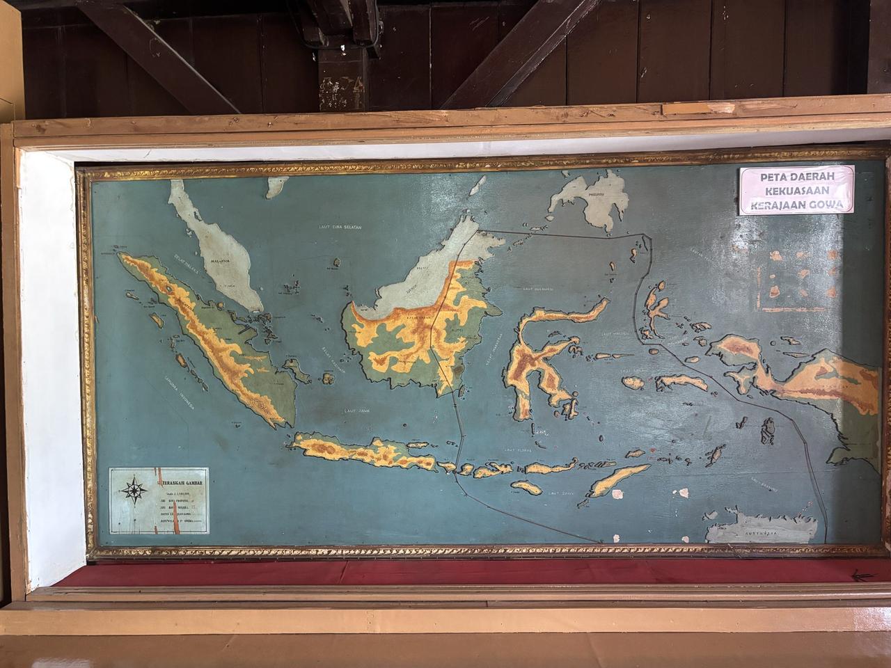 Sebuah peta relief tua yang dilukis di balik kaca, menandai wilayah historis Kerajaan Gowa yang membentang di seluruh Sulawesi dan sekitarnya.