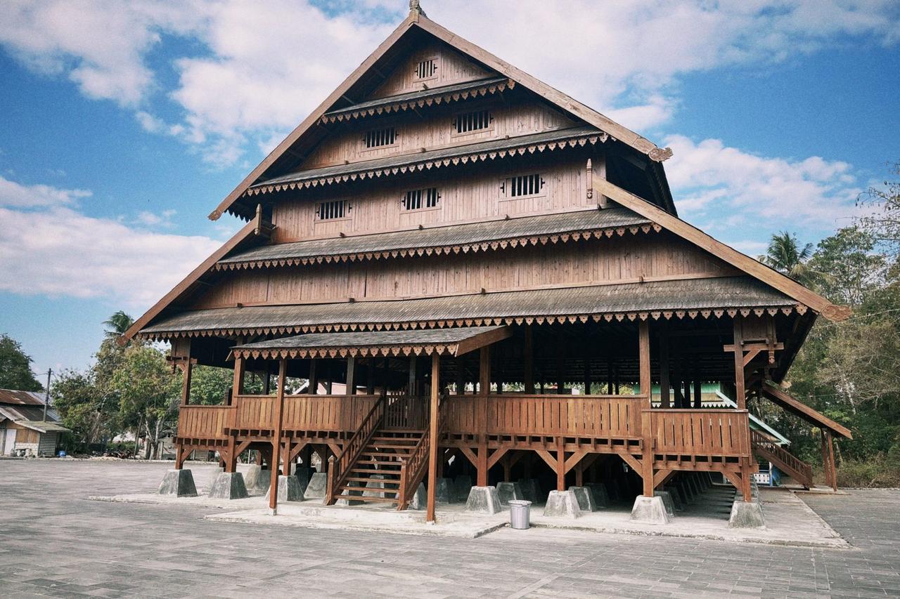 The large wooden Baruga Keraton building inside Benteng Keraton Buton, its tiered roof and open sides raised on stilts.