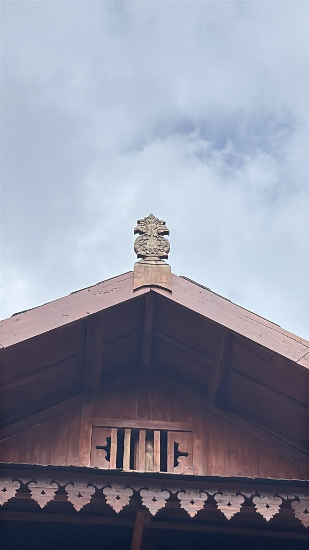 A carved pineapple-shaped finial at the peak of Baruga Keraton's roof, echoing the same succession symbol found at Istana Malige.