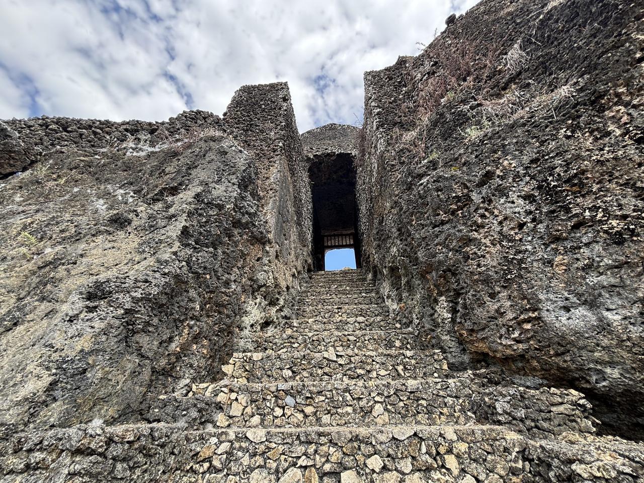 A stone staircase rising steeply through the fortress walls of Benteng Keraton Buton toward an archway at the top.