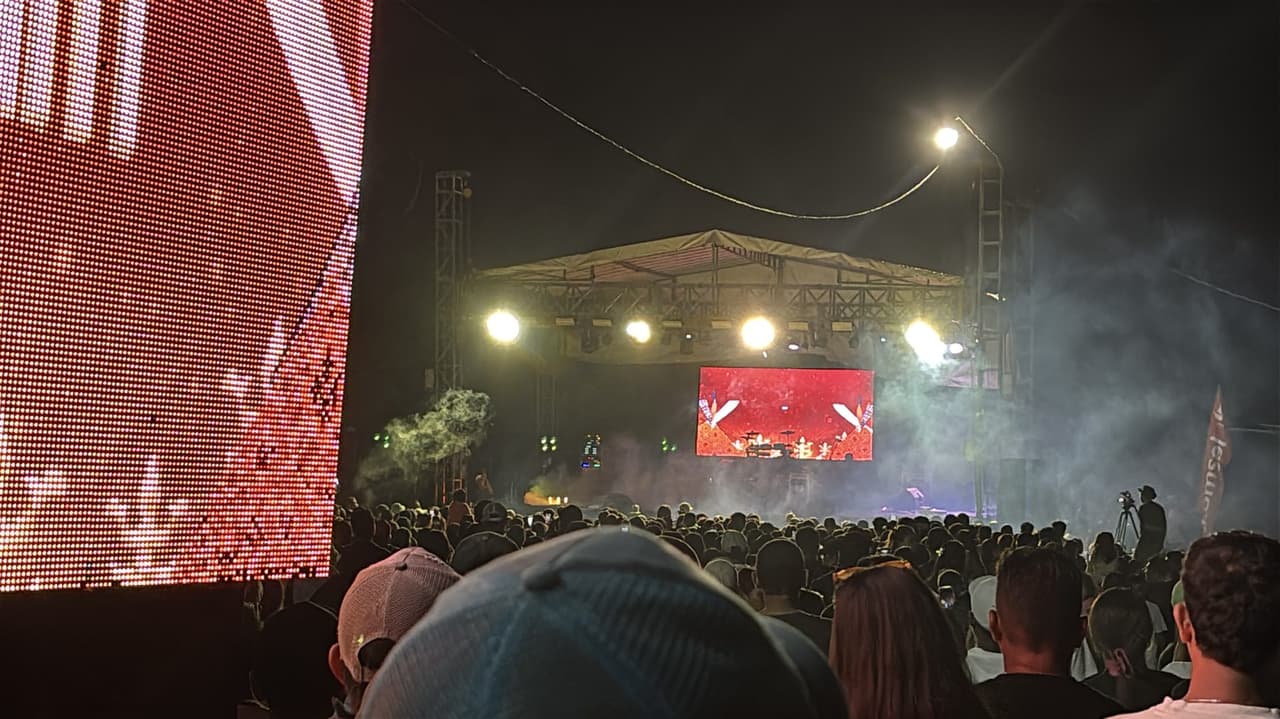 A large nighttime crowd facing a lit stage at the evening concert closing Festival Marawai.