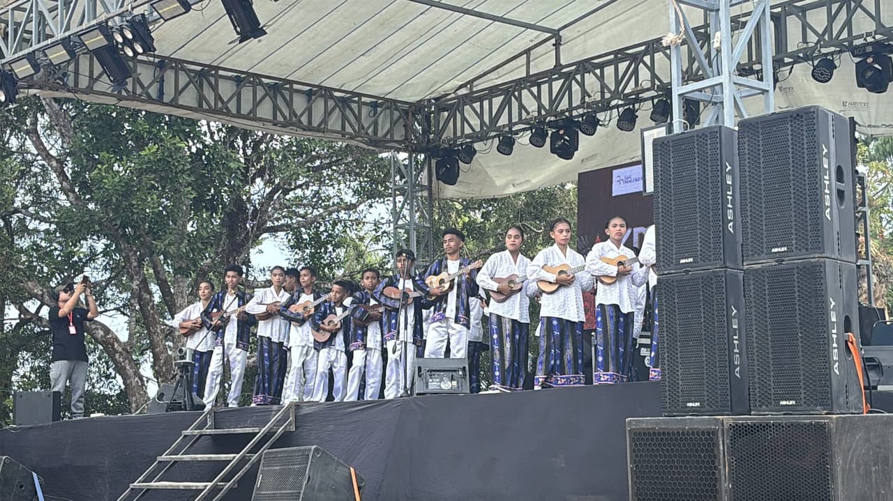 A group of performers in white shirts and traditional blue and gold sarongs playing ukulele together on stage at Festival Marawai.