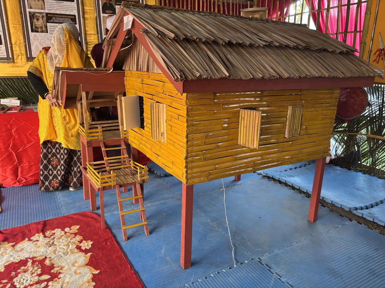 A model of a traditional Kaili stilt house raised on wooden legs with a ladder, displayed beside a historical placard.