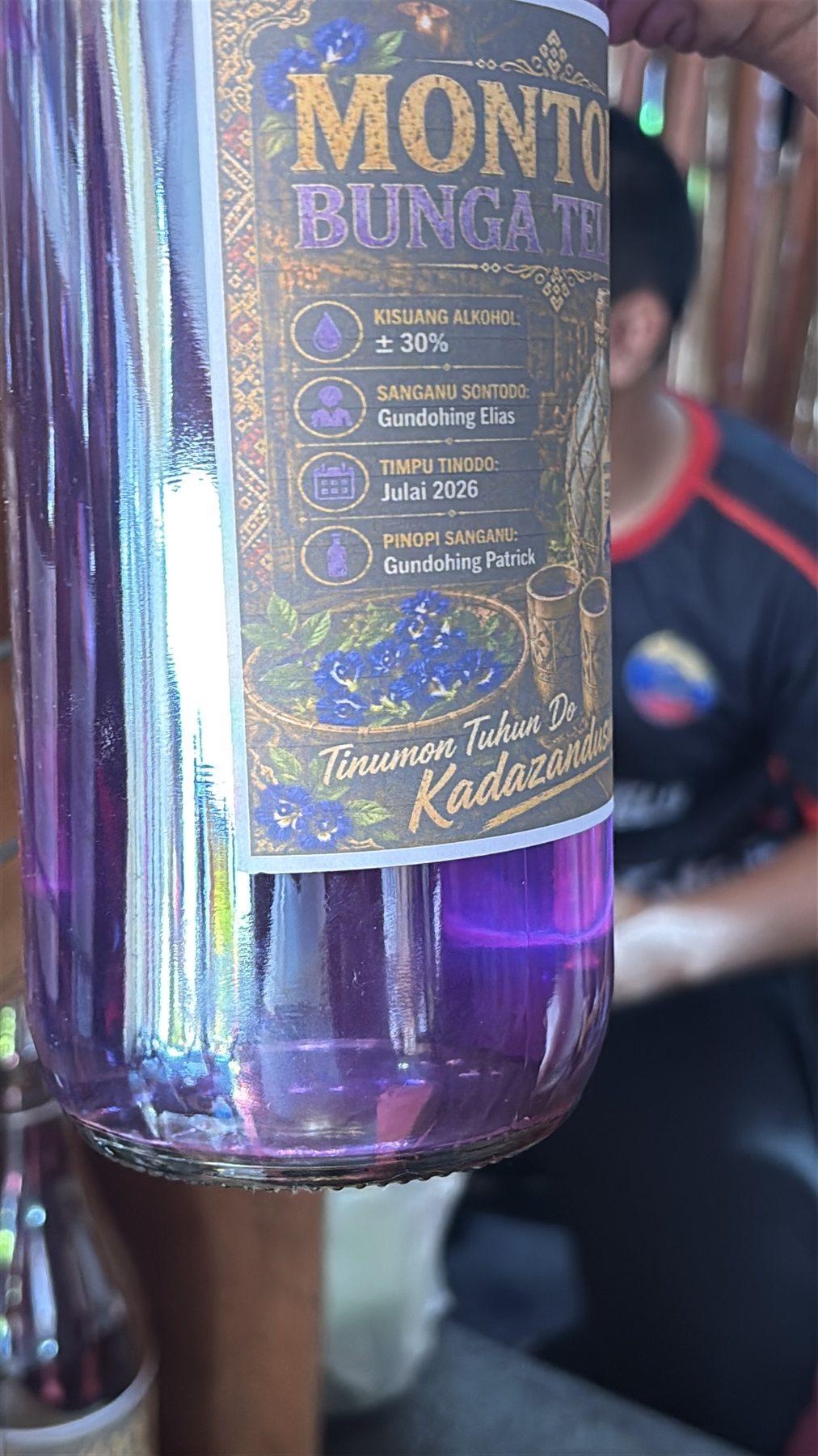A close-up of a Montoku Bunga Telang liquor bottle label, listing alcohol content, brewer's name, and a July 2026 bottling date.