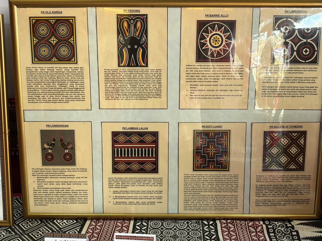 A framed reference board of eight named Toraja woodcarving motifs, each panel showing the carved pattern alongside a written explanation of its meaning.