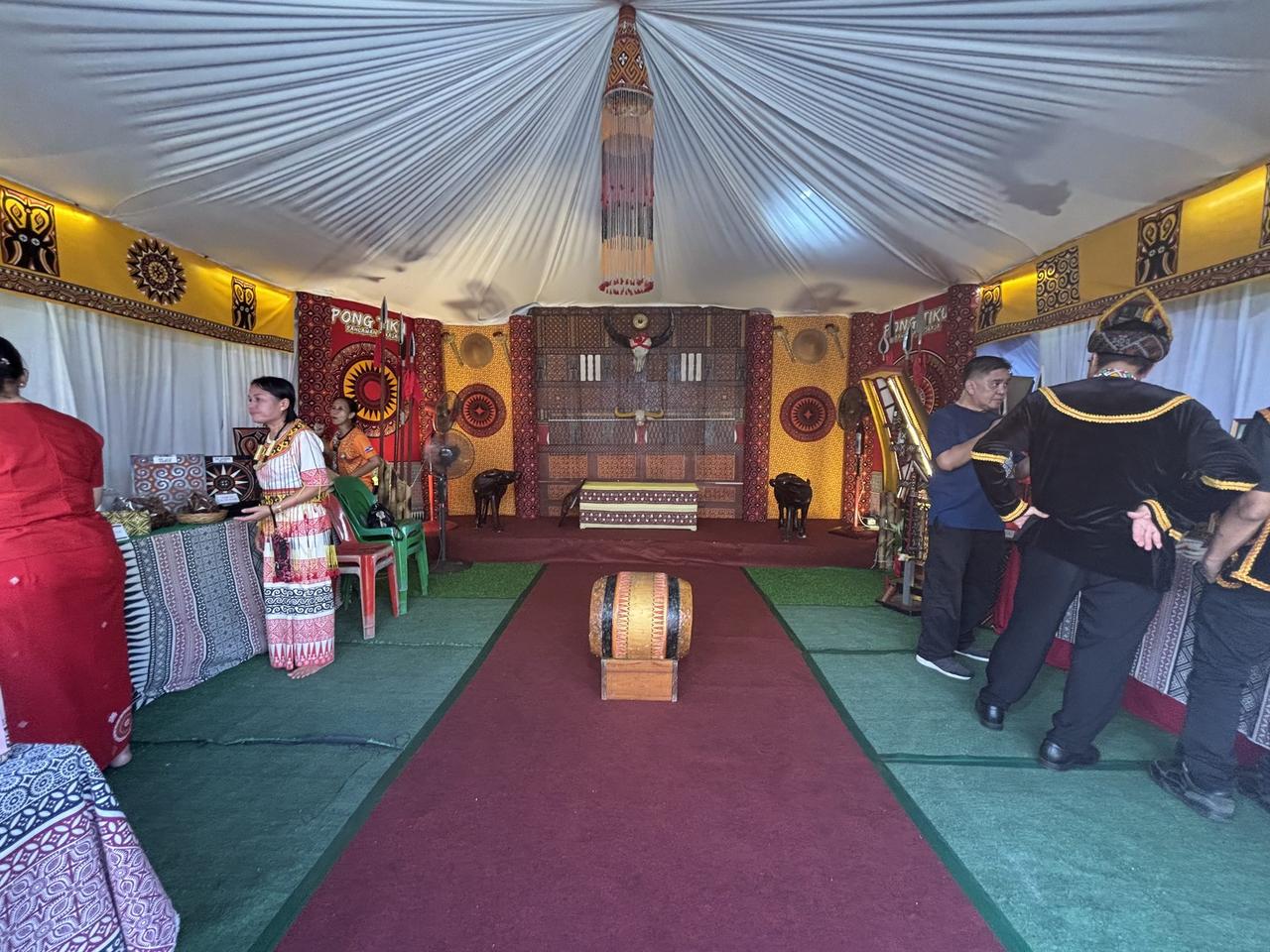 The interior of the Pong Tiku pavilion, a carved buffalo skull mounted on a patterned wall, with gongs and a traditional drum on the floor.