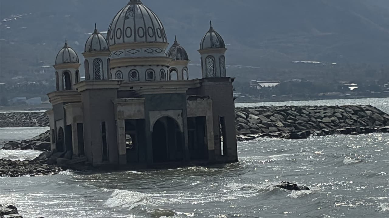 Struktur berkubah masjid terapung yang berdiri di Teluk Palu, tampak rusak dan miring.
