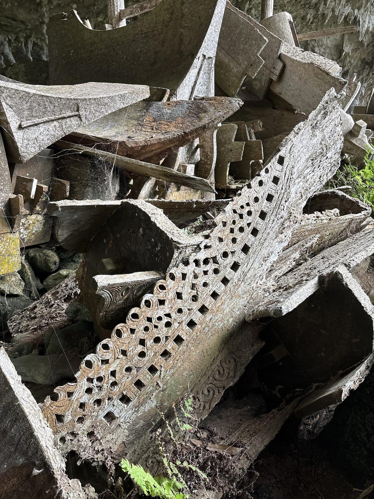 A close-up of an erong's carved end, cut with rows of small circular perforations in an intricate lattice pattern.