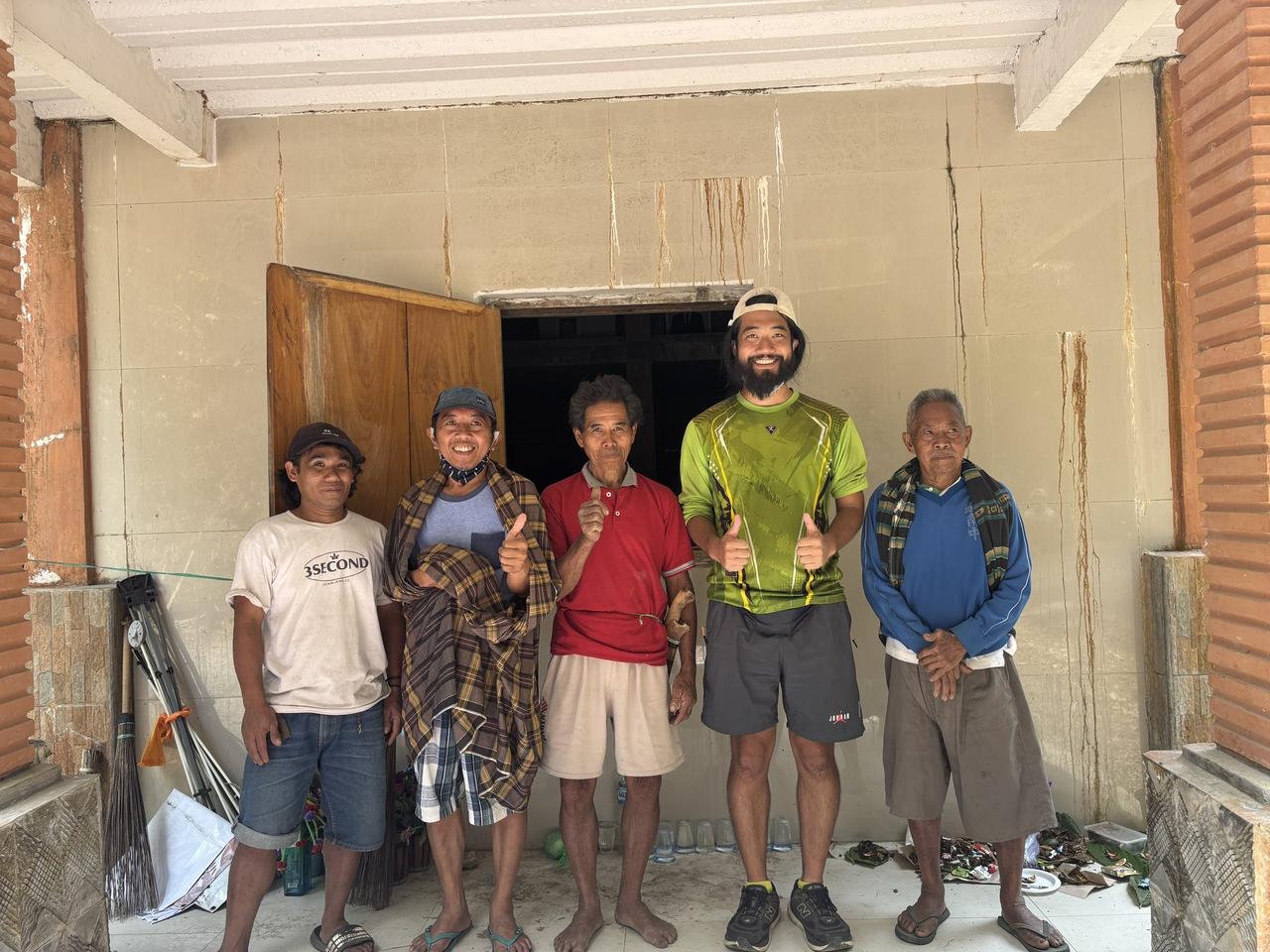Hiro with four local men, thumbs up, standing at the entrance of the tomb building after the day's work.
