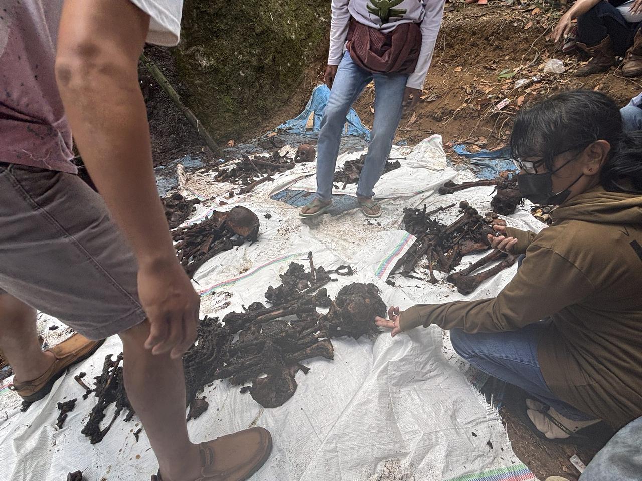 Old bones and a skull laid out on a white tarp beside the tomb, sorted during the cleaning.