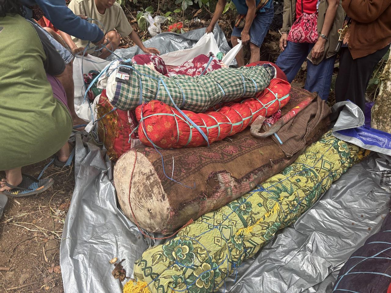 Bodies wrapped in red, green plaid, and yellow floral cloth, tied and bundled, ready to be returned to the tomb.