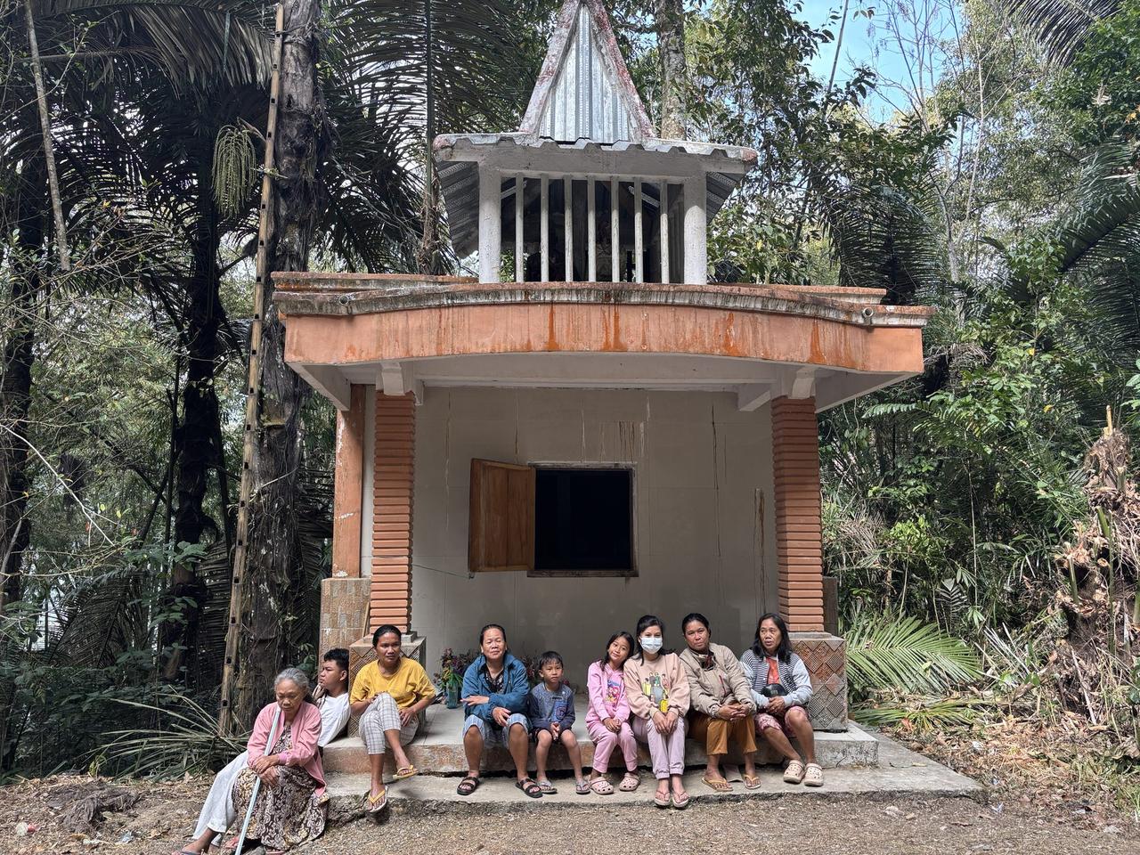 Family members and children sitting together on the steps of the white Patane tomb.