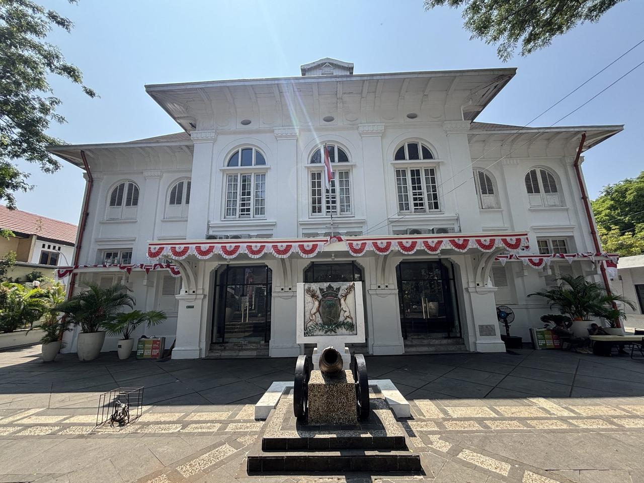 Fasad putih bergaya Art Deco dari bekas Balaikota, kini Museum Kota Makassar, dengan sebuah meriam tua terpasang di pelataran depannya.